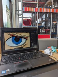 Laptop with Photoshop open drawing sad eye at McDonald's play place